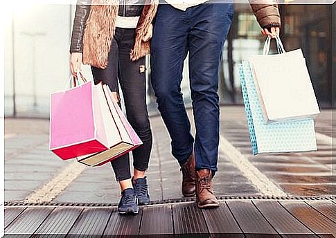 A couple walks with many bags in their hands