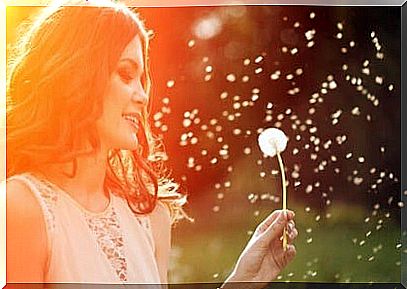 A smiling girl enjoying life stands with a dandelion