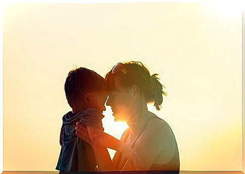 Mother and child hug in front of sun