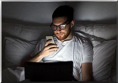 Man in bed with phone and computer