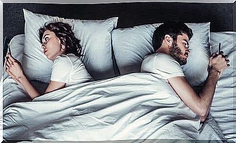 Couples lie in bed with each their phone