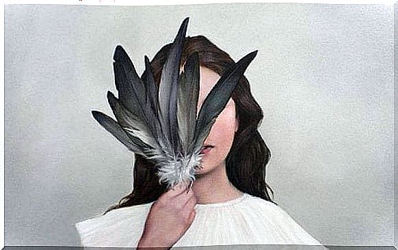 Woman hiding face behind feathers