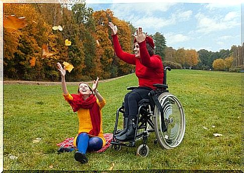 Two women throw with leaves outside and enjoy functional diversity