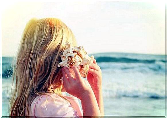 Woman listening in conch by the sea