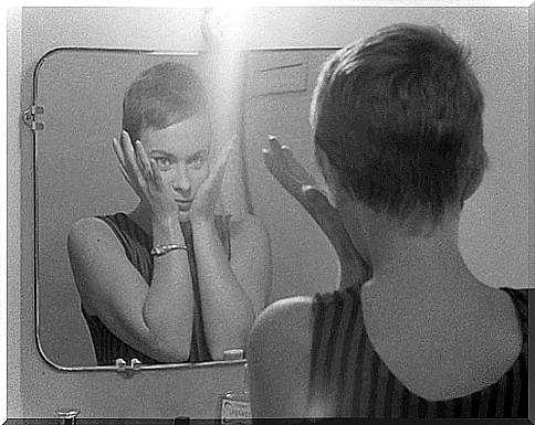 Woman smiles to herself in mirror as she has found peace after the storm