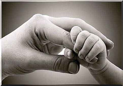 A baby holds his mother's finger