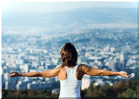 Woman standing with arms outstretched and looking at city