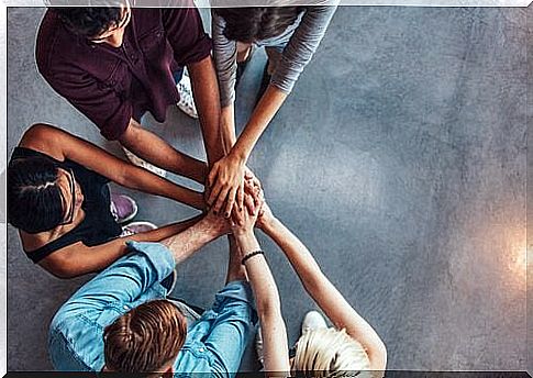 Group of people standing with hands together