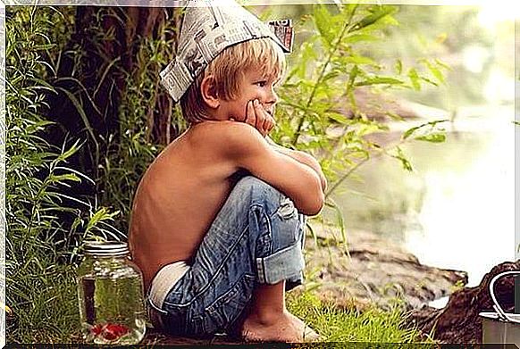 A boy is squatting with a newspaper hat on