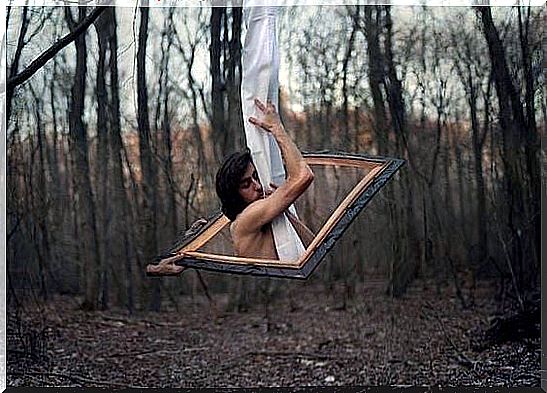 Man in a frame in a forest clings to a piece of fabric and tries to appreciate what he has