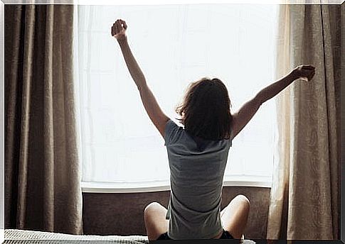 Woman stretching arms over head in front of window