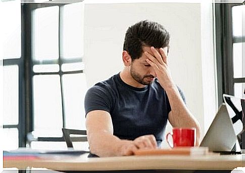 Man has headache due to stressors in the workplace