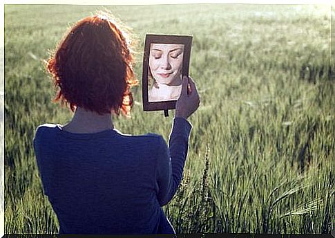 A woman is holding a mirror in a field